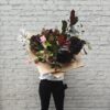 Close-up of a woman holding the Show Stopper bouquet, highlighting the scale and lush textures of the large, seasonal British flowers in rich, moody and romantic tones