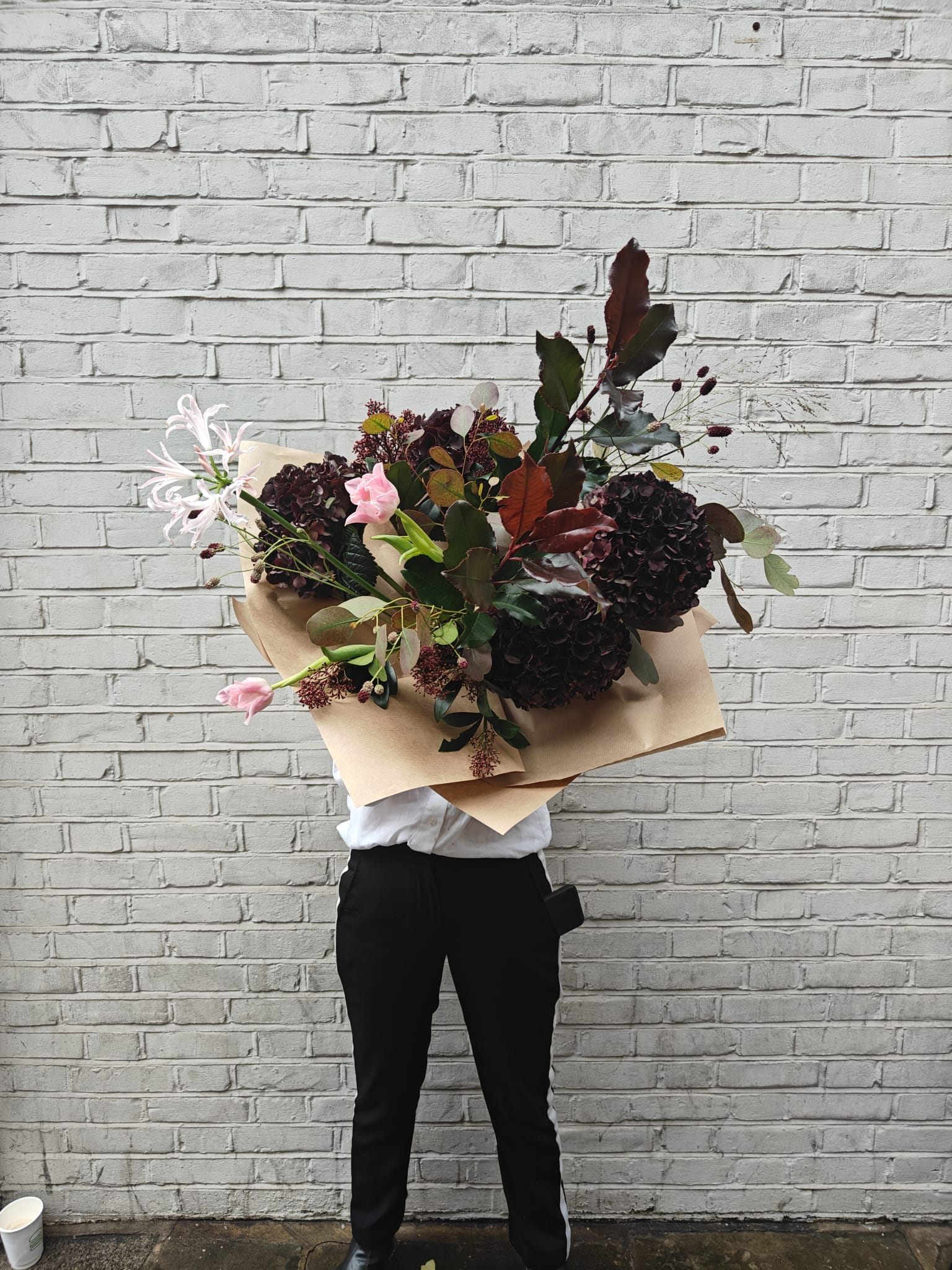 Close-up of a woman holding the Show Stopper bouquet, highlighting the scale and lush textures of the large, seasonal British flowers in rich, moody and romantic tones